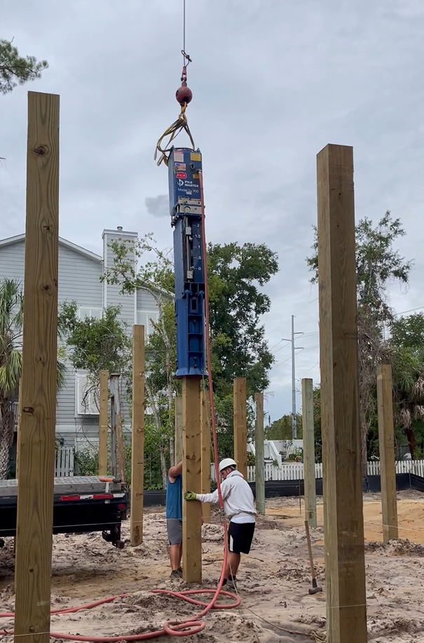 Two men working on a Model 24-900 lifted by a crane on a wooden post.